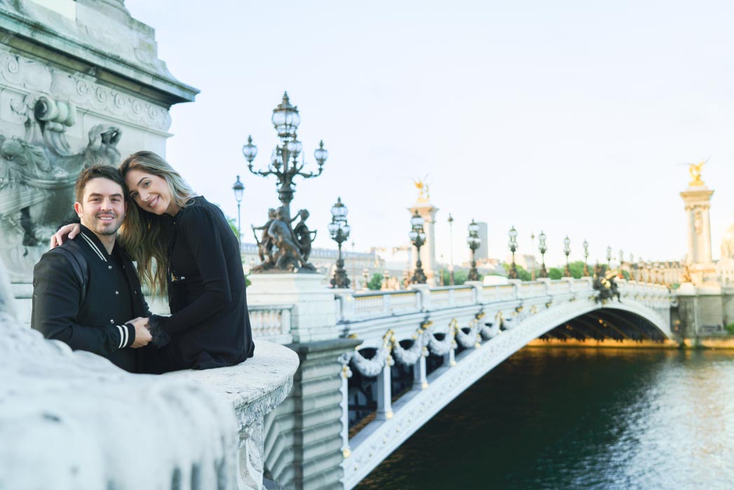 Séance photo couple sur le Pont Alexandre III à Paris avec vue sur l'arche du Pont Alexandre III à Paris, les candélabres