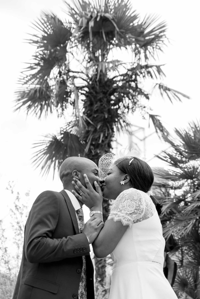 Photo de mariage en noir et blanc – Mariés s’embrassant sur le parvis de la mairie de Paris 13e, par un photographe professionnel