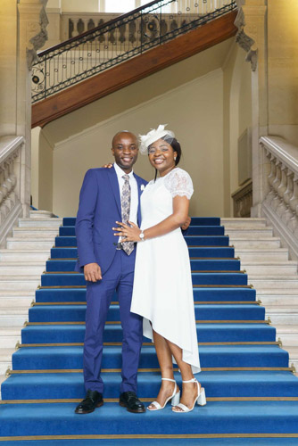 Couple de mariés souriant dans les escaliers intérieurs bleus de la mairie de Paris 13e