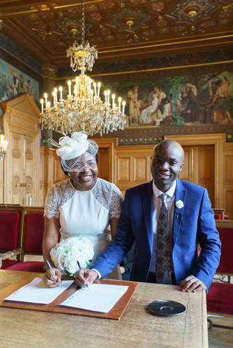 Photographe mariage Paris 13e – Couple de mariés signant le registre lors de leur cérémonie de mariage civil, sourires et émotion