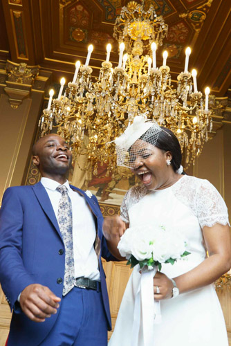 Photo de mariage Paris 13e – Mariés riant lors de leur cérémonie civile sous un lustre doré