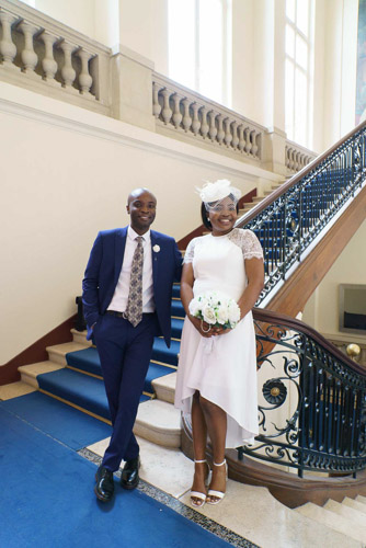 Photographe mariage Paris 13e – Couple de mariés heureux posant dans les escaliers intérieurs de la mairie de Paris 13e