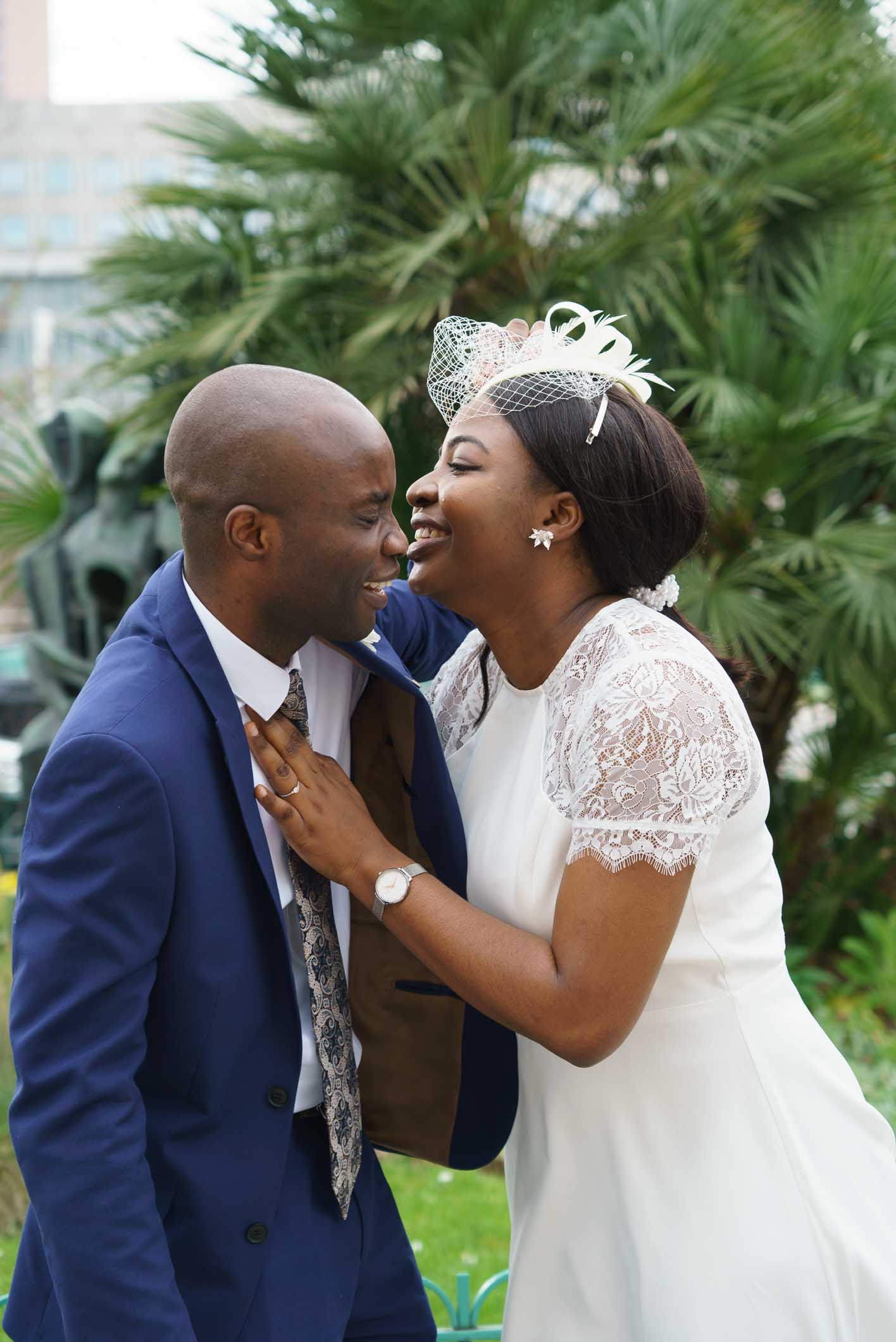 Photographe mariage Paris 13e – Photo d’un couple de mariés s’embrassant devant un palmier sur le parvis de la mairie 13e paris