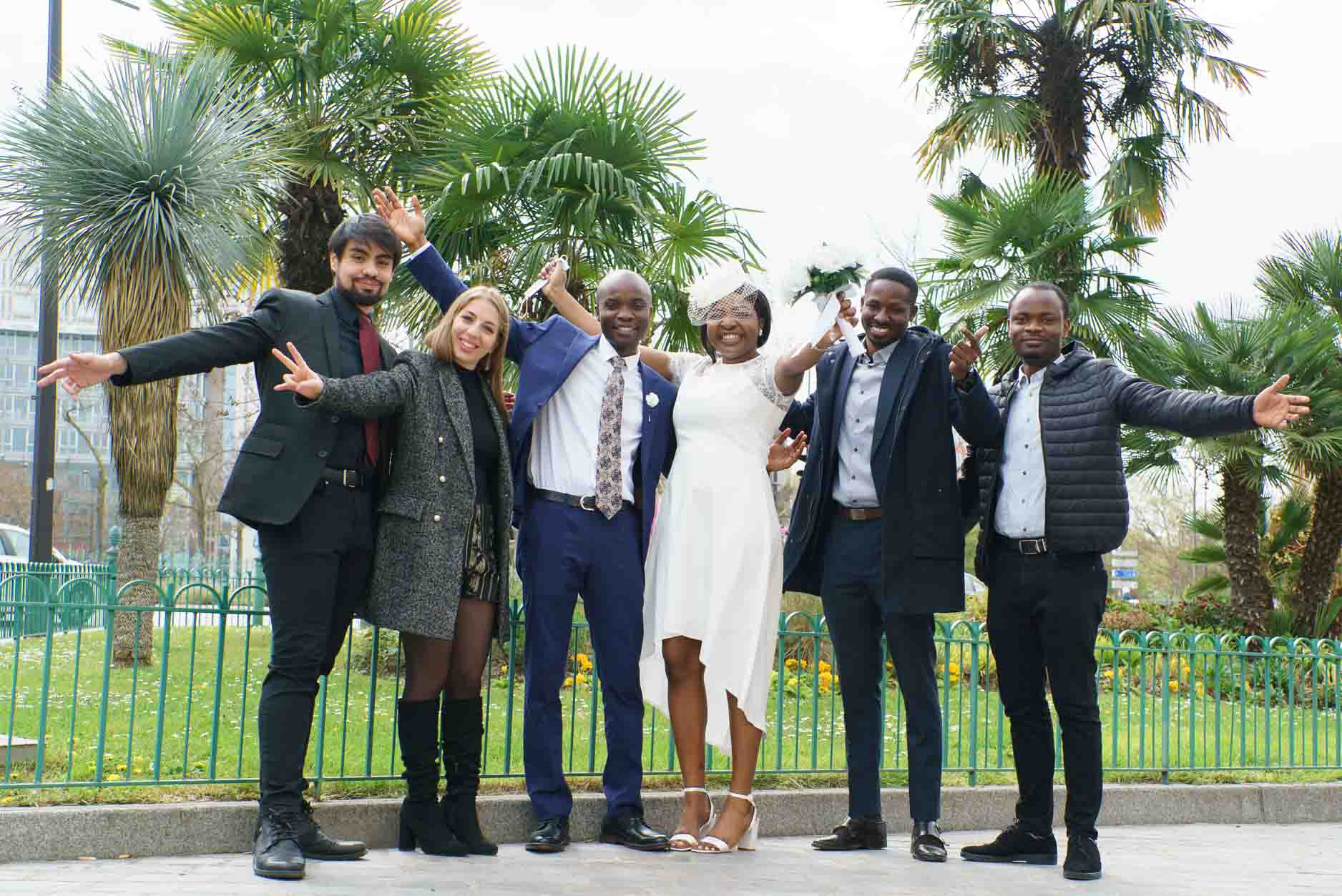 Photographe mariage Paris 13e – Photo de groupe d'invités rigolote sur le parvis de la mairie du 13e arrondissement de Paris lors d'un mariage