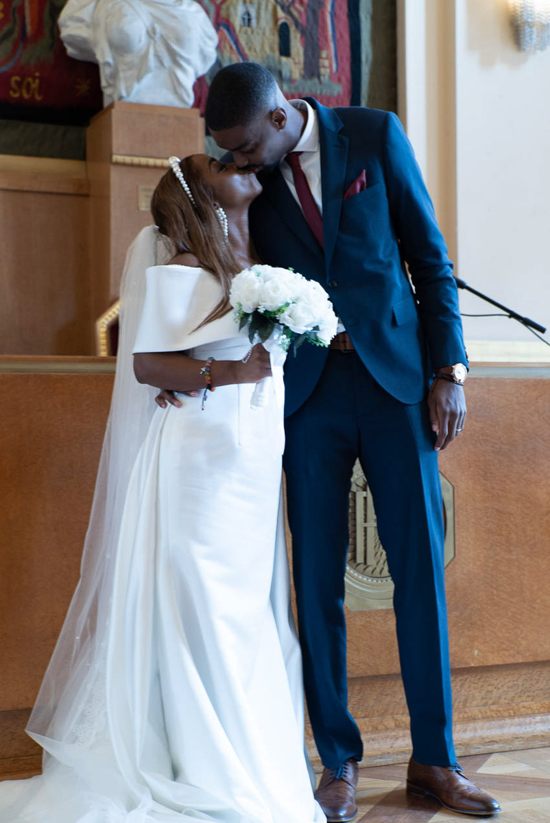 Photographe mariage Paris, couple échange un baiser dans la salle de mariage de la Mairie