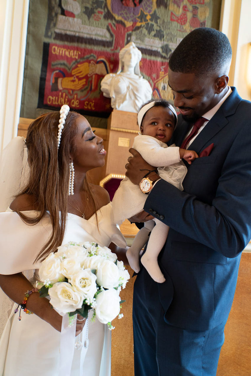 Le couple de mariés avec leur bébé souriant à la mairie de Paris