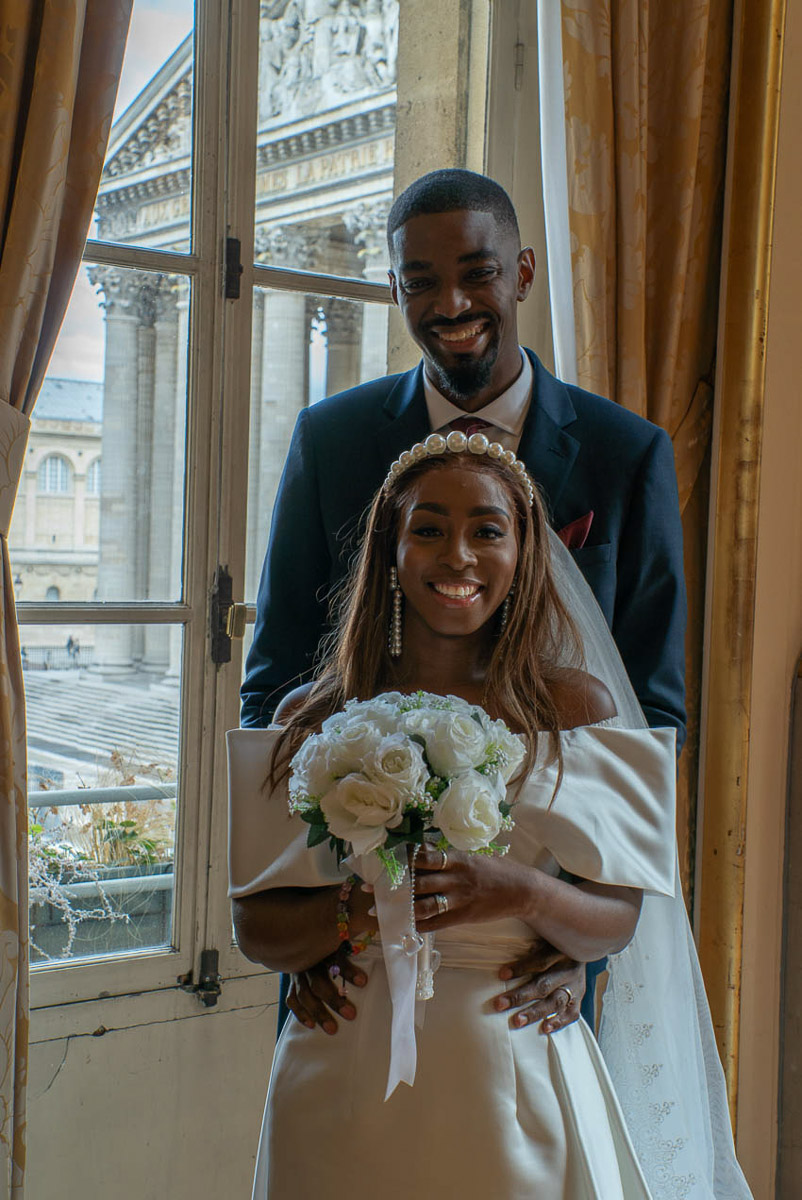 Le couple souriant avec les mains sur le ventre de la mariée